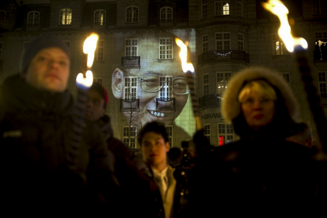 TO GO WITH Year-2010-China FOCUS by Pascale Trouillaud (FILES) In a file picture taken on December 10, 2010 a portrait of Nobel Laureate and jailed Chinese dissident Liu Xiaobo is projected on a wall of a hotel as a torch parade in his honour passes by in Oslo. China solidified its financial might in 2010, becoming the world's second-largest economy, but it was often inflexible and isolated on the political stage -- an intransigence typified by the Nobel peace prize drama. Beijing was furious that jailed dissedent Liu was honoured, calling members of the Oslo-based Nobel committee "clowns". It blacked out foreign TV coverage of the ceremony, calling it an example of "political theatre".  AFP PHOTO / ODD ANDERSEN / AFP PHOTO / ODD ANDERSEN